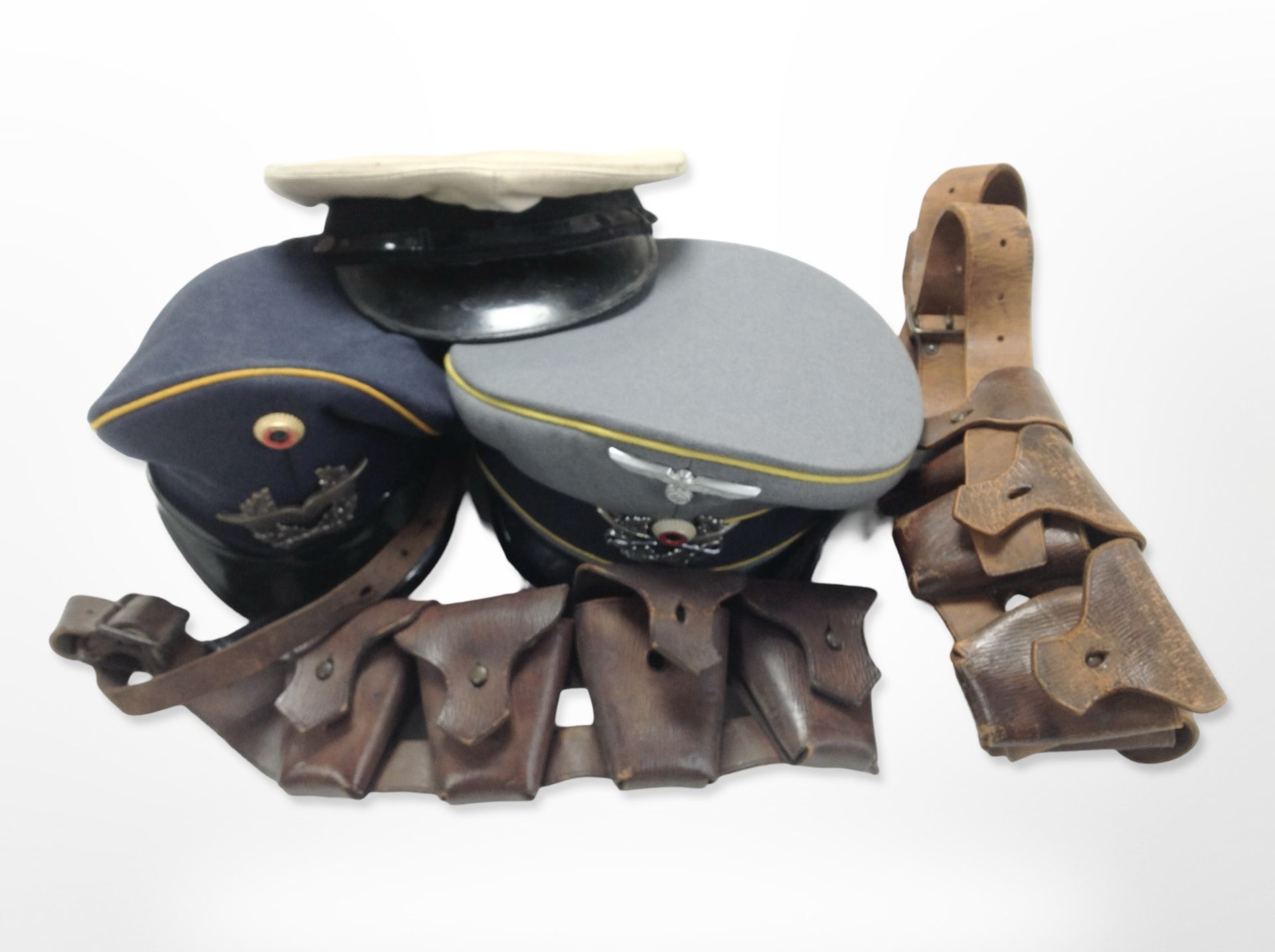 A reproduction German cap, two further caps, and two 20th-century ammunition belts.