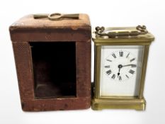 A brass-cased carriage timepiece with key, height 14cm including handle, in leather travel case.