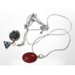 A silver-mounted red polished stone necklace and a further necklace with triangular pendant.