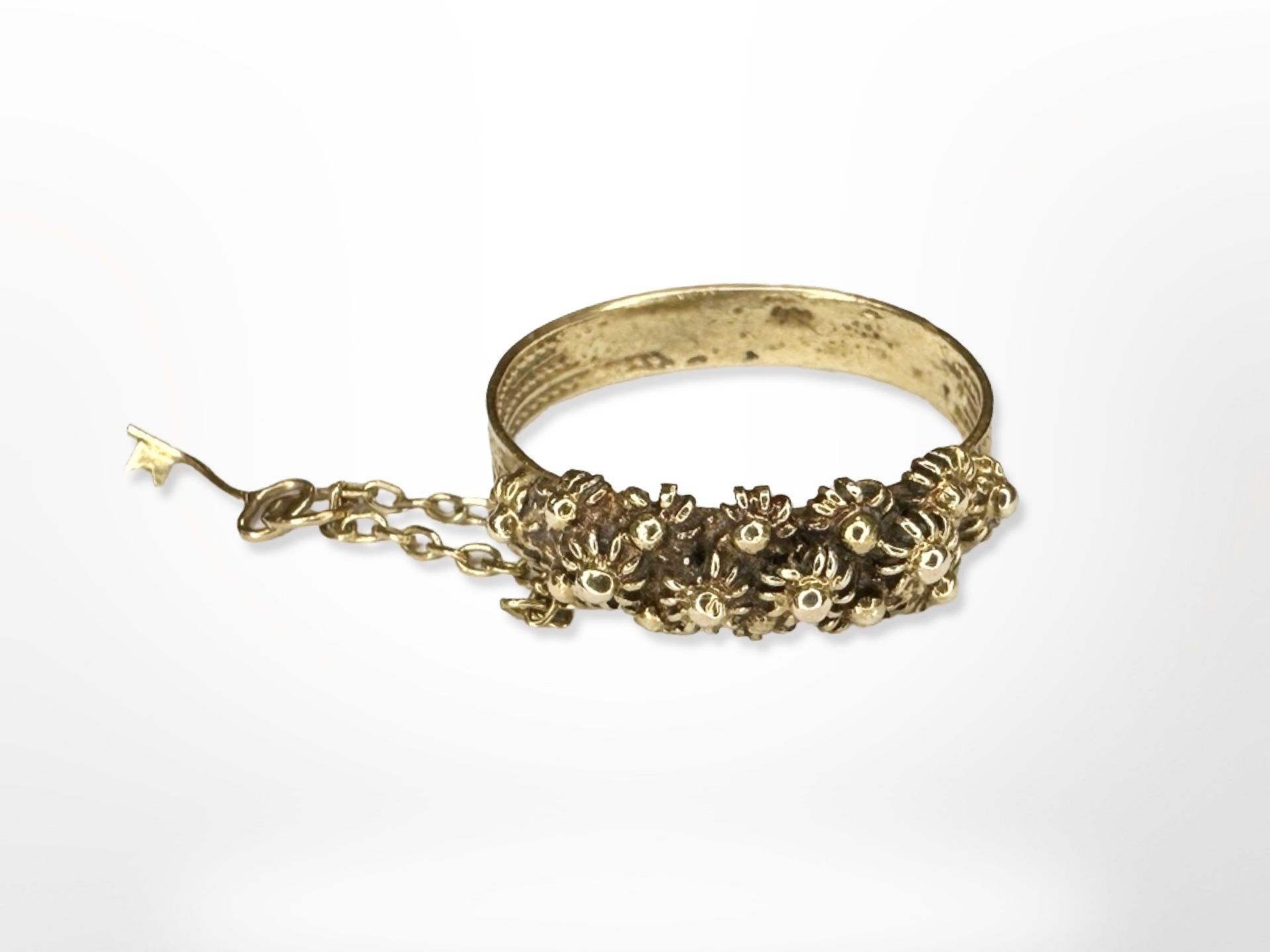 An ornate yellow metal band ring with safety chain and key, size J.