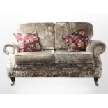 A contemporary Victorian style two seater settee in plush fabric with two cushions raised on brass