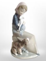 A Lladró figure of a girl holding a lamb with a dog at her feet.