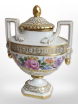 A Dresden hand-painted and gilt floral twin-handled lidded urn, height 19cm.