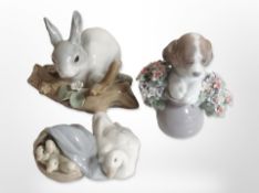 Three Lladró animal figures including goose with goslings, puppy and rabbit.