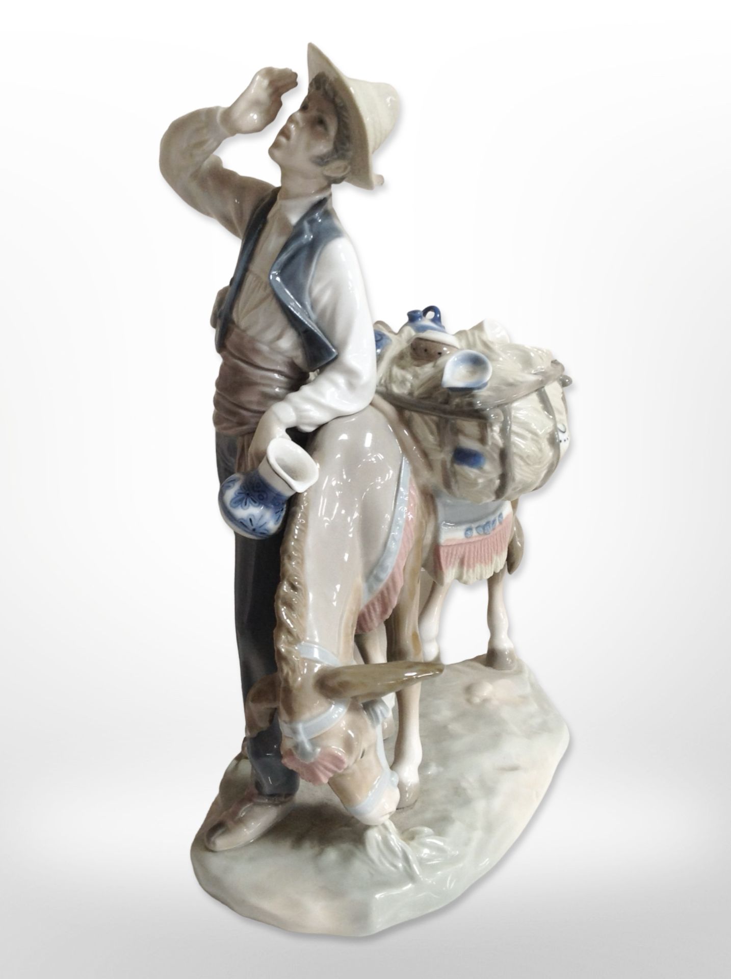 A Lladró figure of a man with a mule carrying goods.