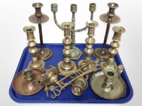 A collection of brass and copper candlesticks