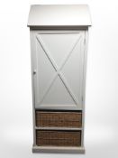 A Cotswold Furniture Company white painted sentry door cupboard with two wicker drawers beneath,