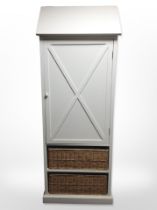 A Cotswold Furniture Company white painted sentry door cupboard with two wicker drawers beneath,