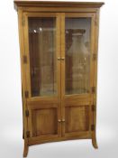 A contemporary glazed double door cabinet fitted with cupboards beneath,