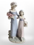 A Lladró figure of two girls carrying flowers.
