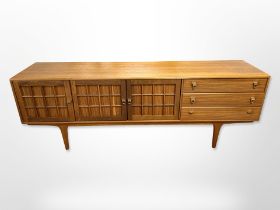 A Younger teak low sideboard fitted three cupboard doors and three drawers on tapered legs,