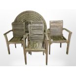 A weathered teak circular garden table and a set of four armchairs