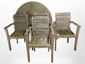 A weathered teak circular garden table and a set of four armchairs