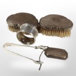 Two silver-backed dressing table brushes, a napkin ring, a pair of sugar tongs,