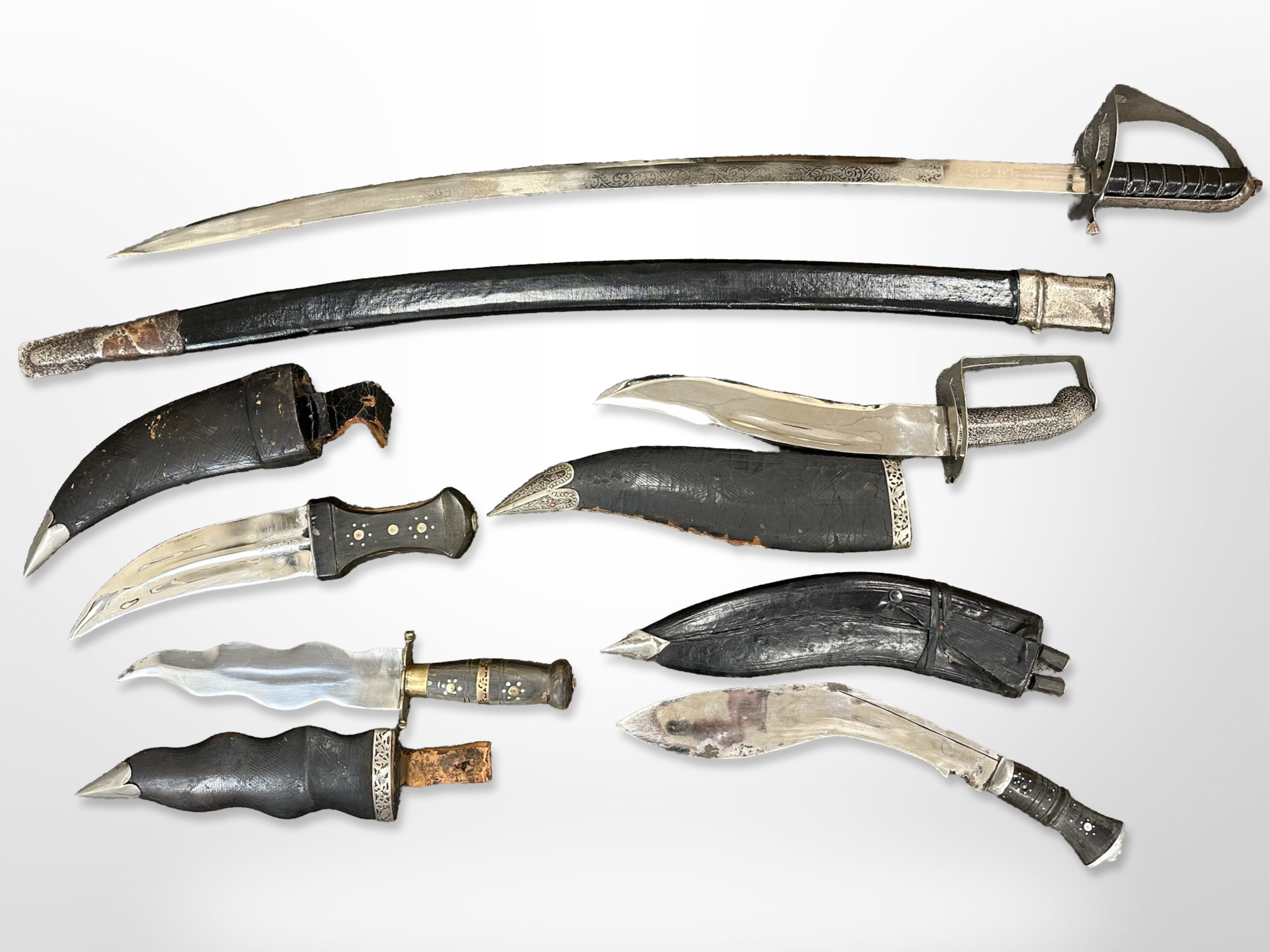 An Indian sabre in scabbard with 73cm blade, together with two further Indian-made kukris,