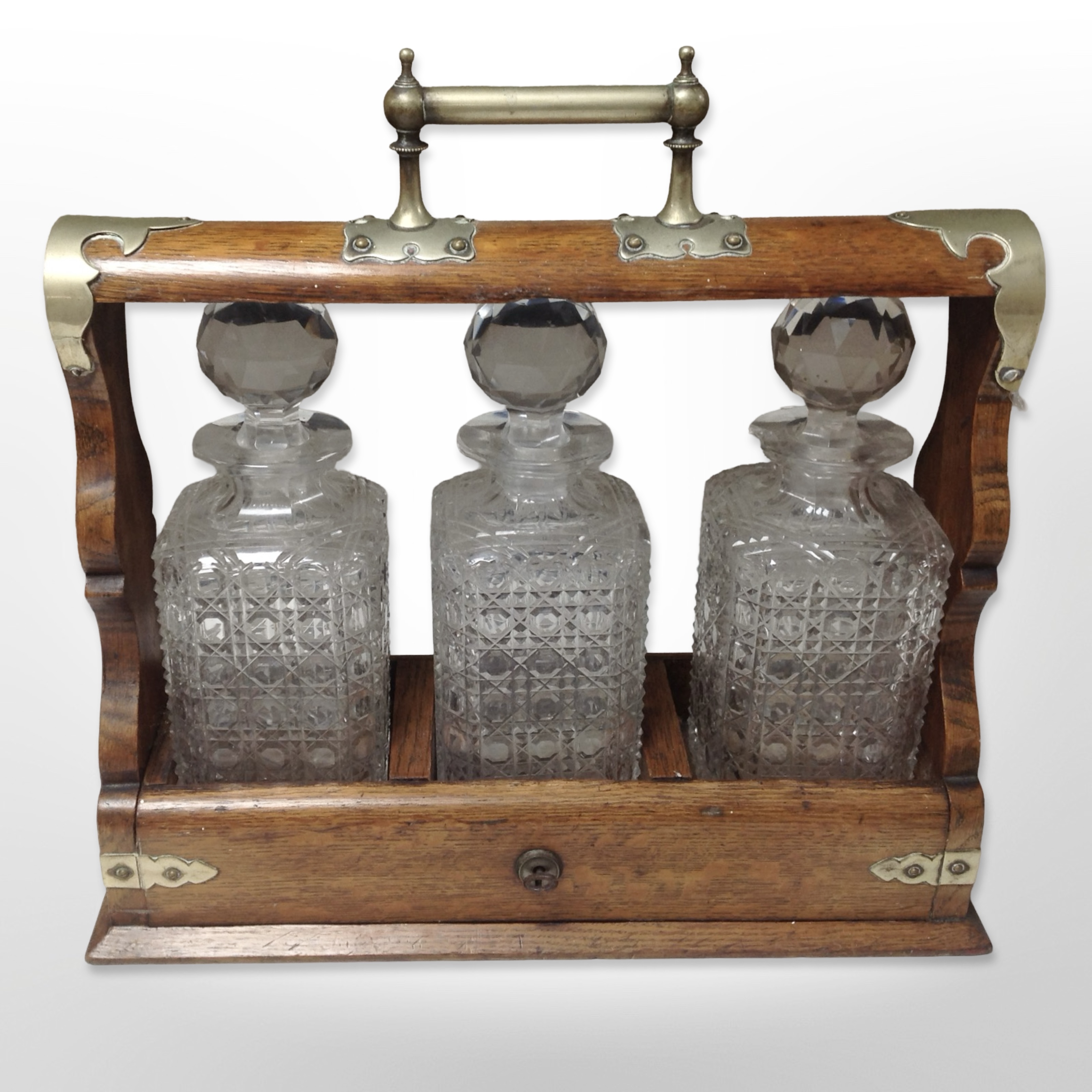 An oak and silver plate-mounted tantalus containing three decanters, width 37cm.