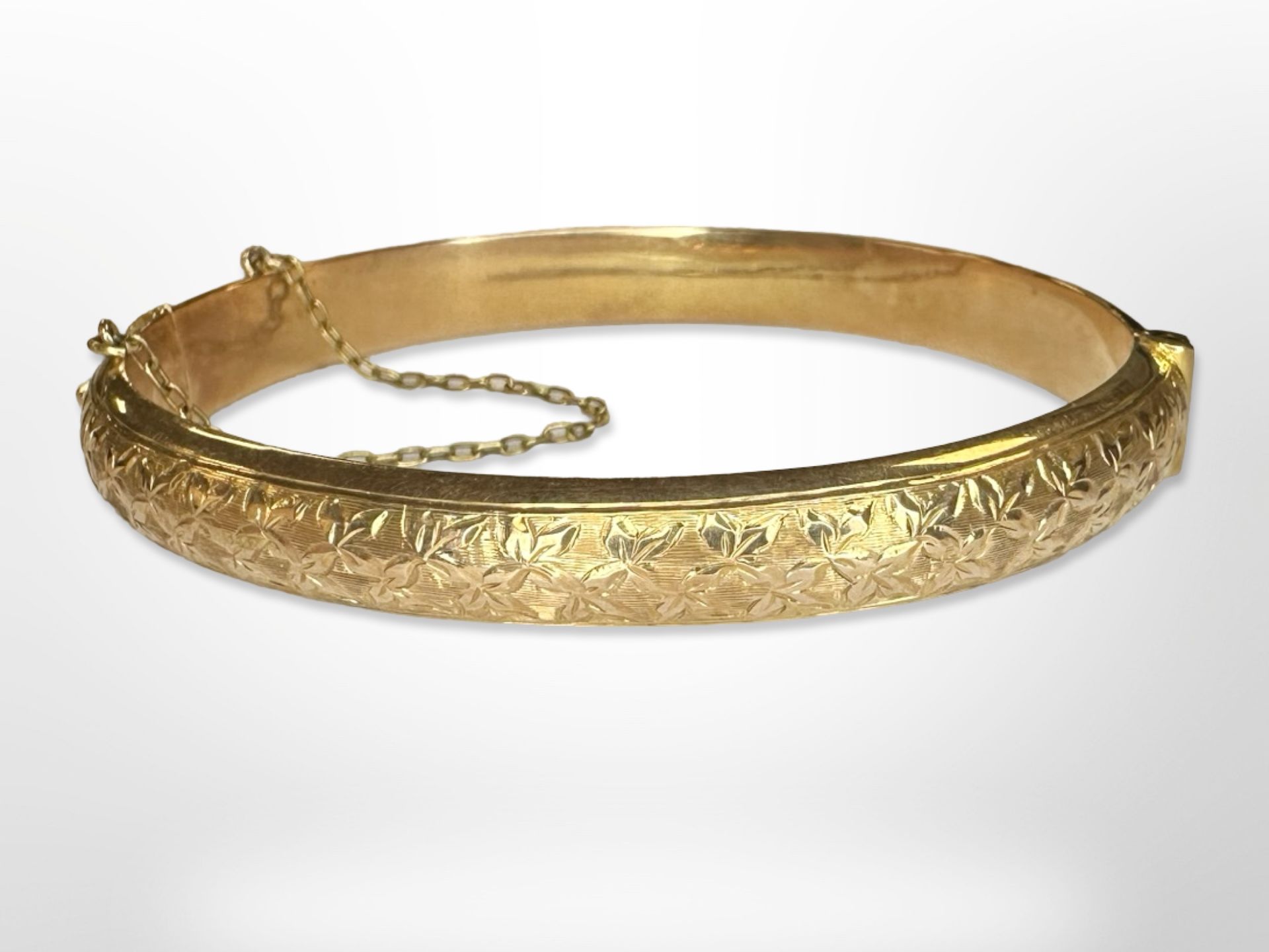 An antique 15ct yellow gold bangle, with lightly engraved floral decoration, internally 6 cm x 5 cm.