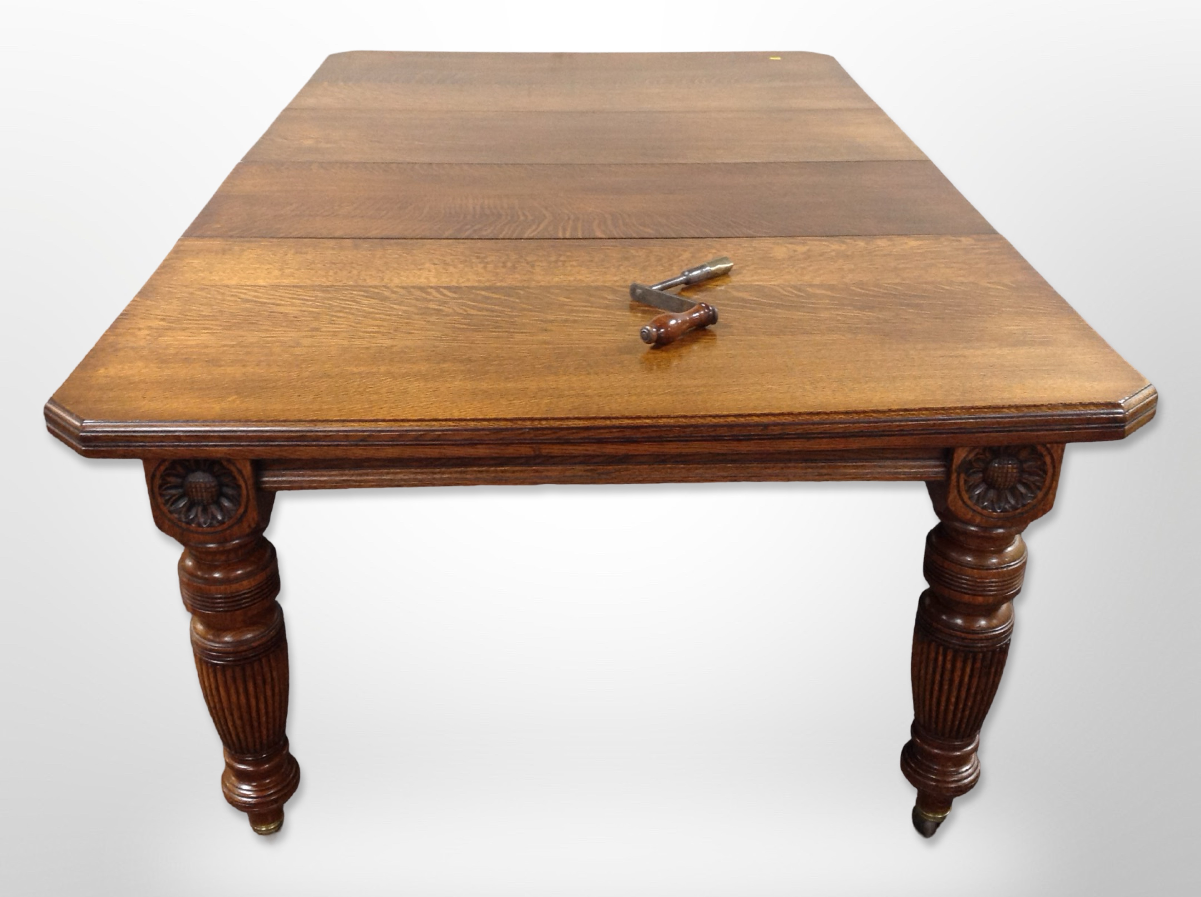 A good quality Edwardian carved oak extending dining table with two leaves and winder,