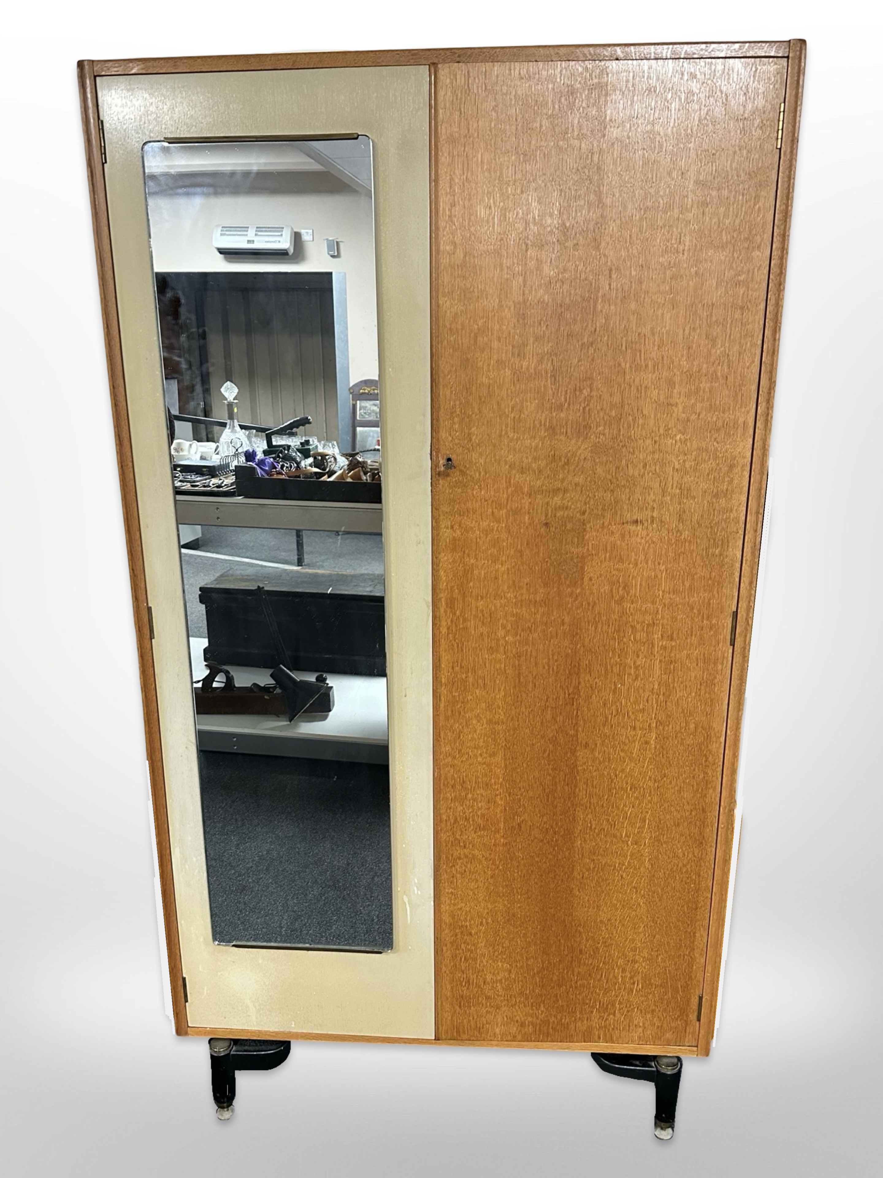 A vintage G Plan oak and teak mirror door wardrobe, designed by E Gomme, raised on ebonised legs,