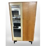 A vintage G Plan oak and teak mirror door wardrobe, designed by E Gomme, raised on ebonised legs,