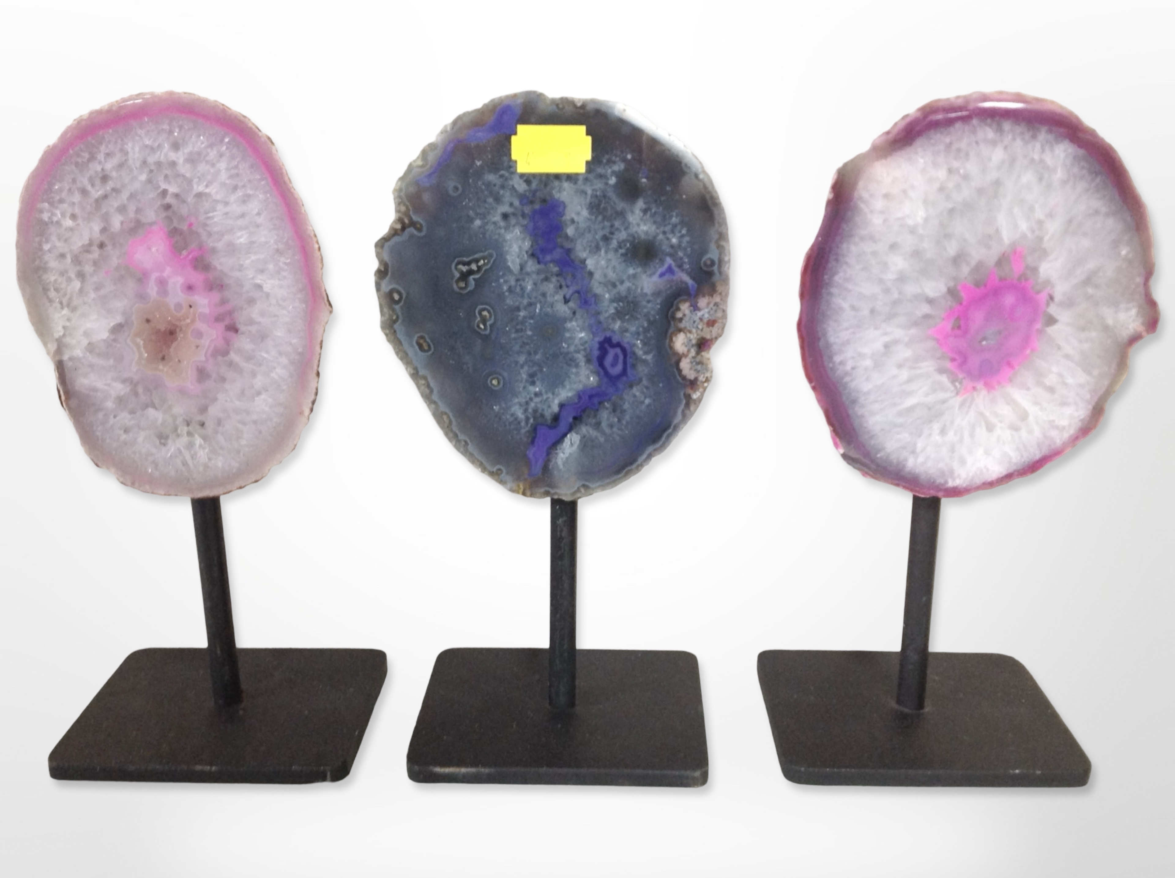 Three sliced and polished gemstone specimens on stands, height 22cm.