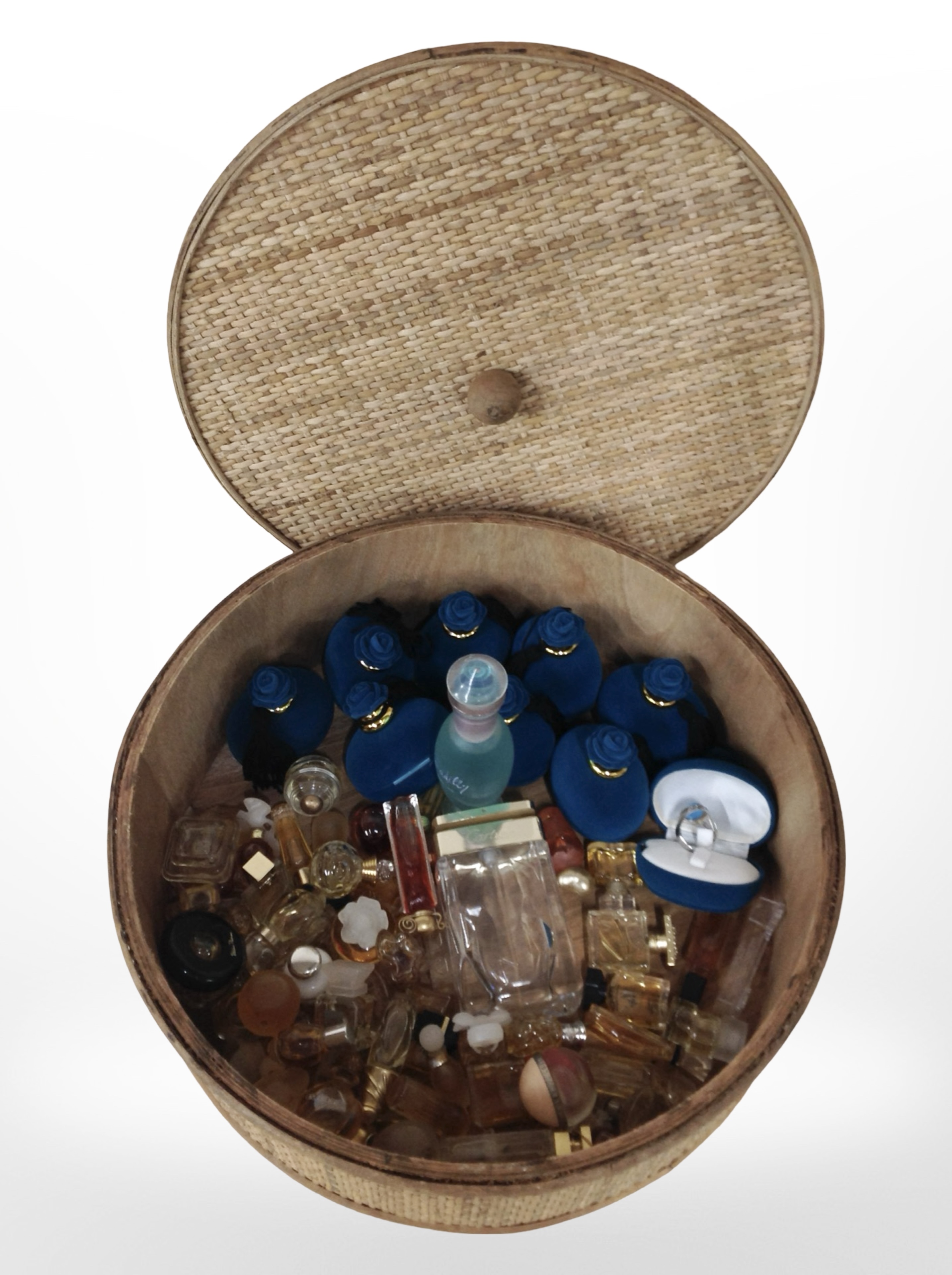 A circular wicker lidded basket containing a quantity of silver dress rings and assorted miniature