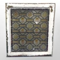 A stained leaded glass window in distressed painted frame, overall 58cm x 66cm.