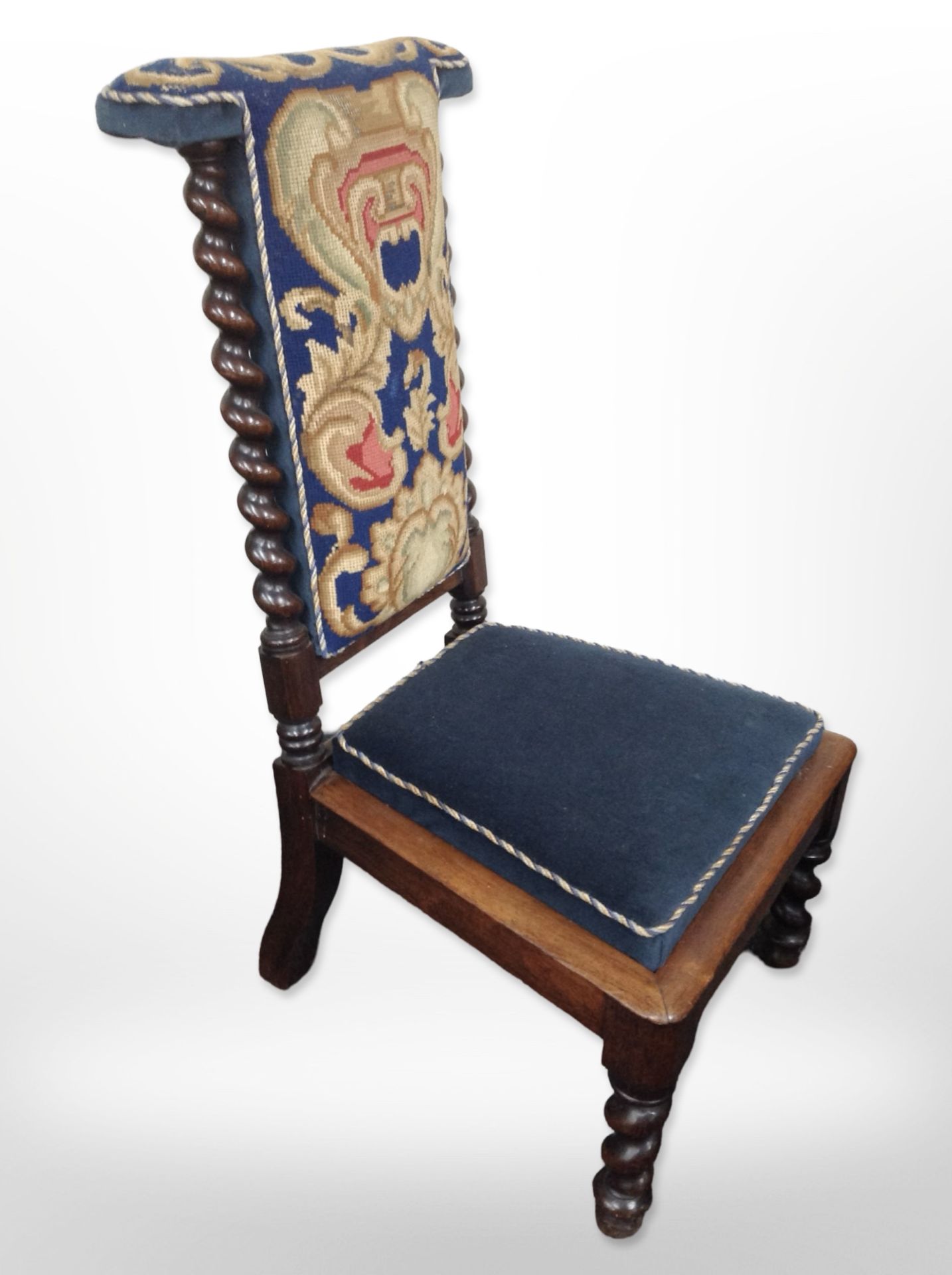 A 19th-century carved rosewood prie-dieu in tapestry needlework upholstery.