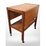 A 20th-century teak and ply drop-leaf trolley on castors,