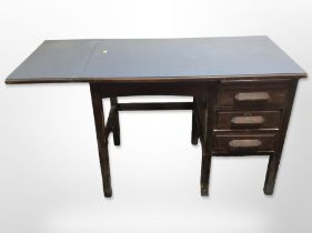 A mid-20th century oak drop-leaf extending single-pedestal desk, with melamine top,