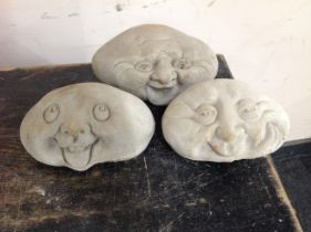Three graduated concrete happy face ornaments,