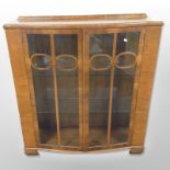 An Art Deco walnut bow-front display cabinet, 105cm wide x 35cm deep x 117cm high.