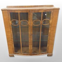An Art Deco walnut bow-front display cabinet, 105cm wide x 35cm deep x 117cm high.