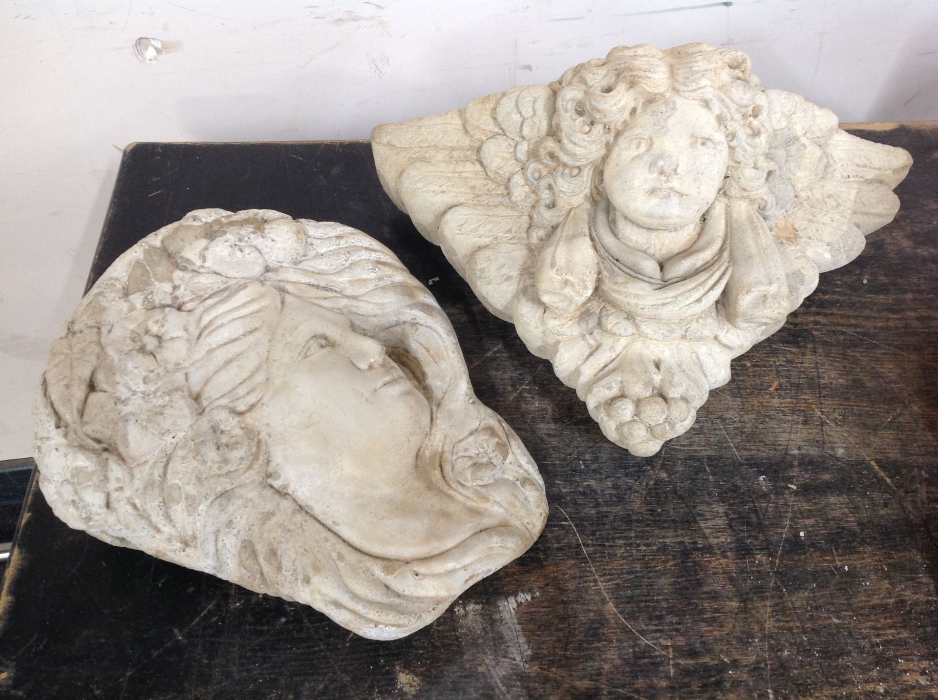 A concrete cherub wall pocket and further plaque depicting a maiden,