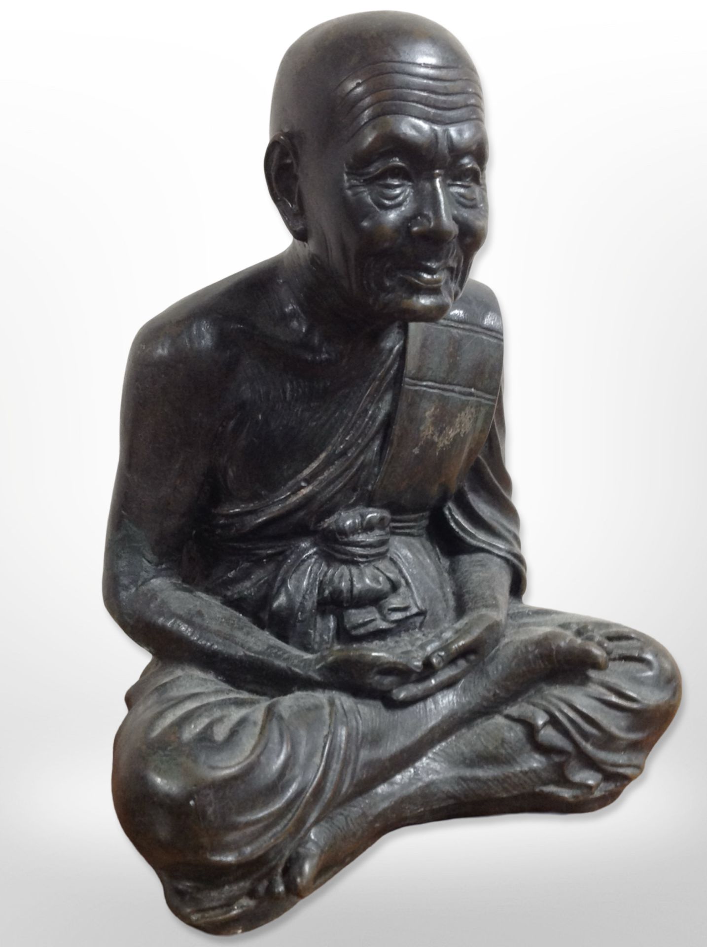 A patinated metal figure of a seated monk, height 28cm.
