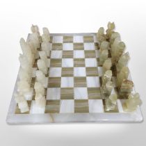 A polished onyx chessboard and pieces, width 37cm.
