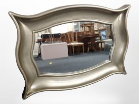 A large contemporary overmantle mirror in swept silvered frame, 134cm wide x 96cm high.