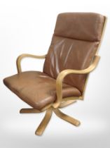 A Stouby bentwood-framed tan stitched leather swivel armchair.