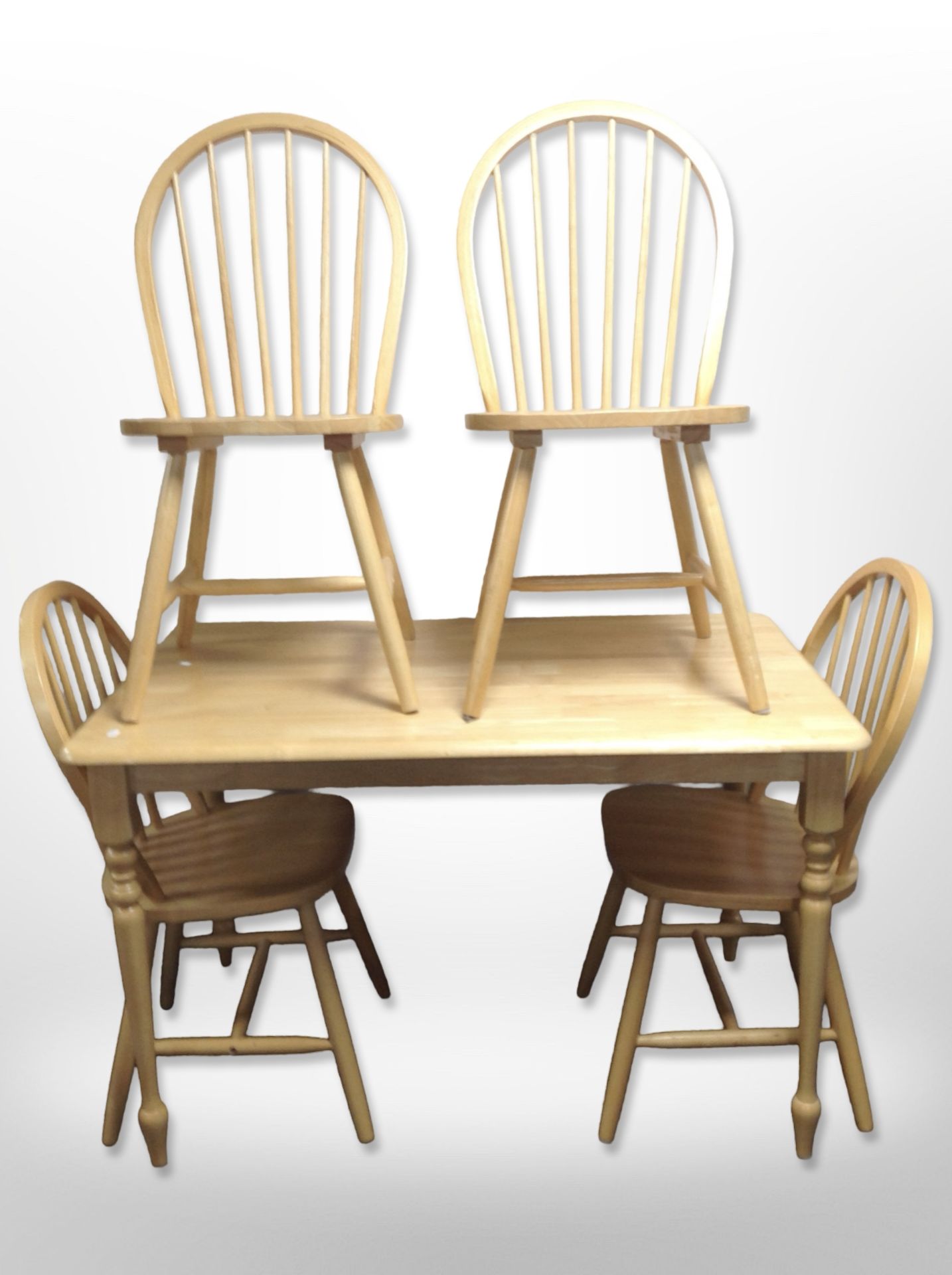 A contemporary pine kitchen table, length 120cm, together with a set of four spindle back chairs.