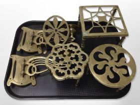Four brass trivets and a pair of Art Nouveau brass wall candle sconces.