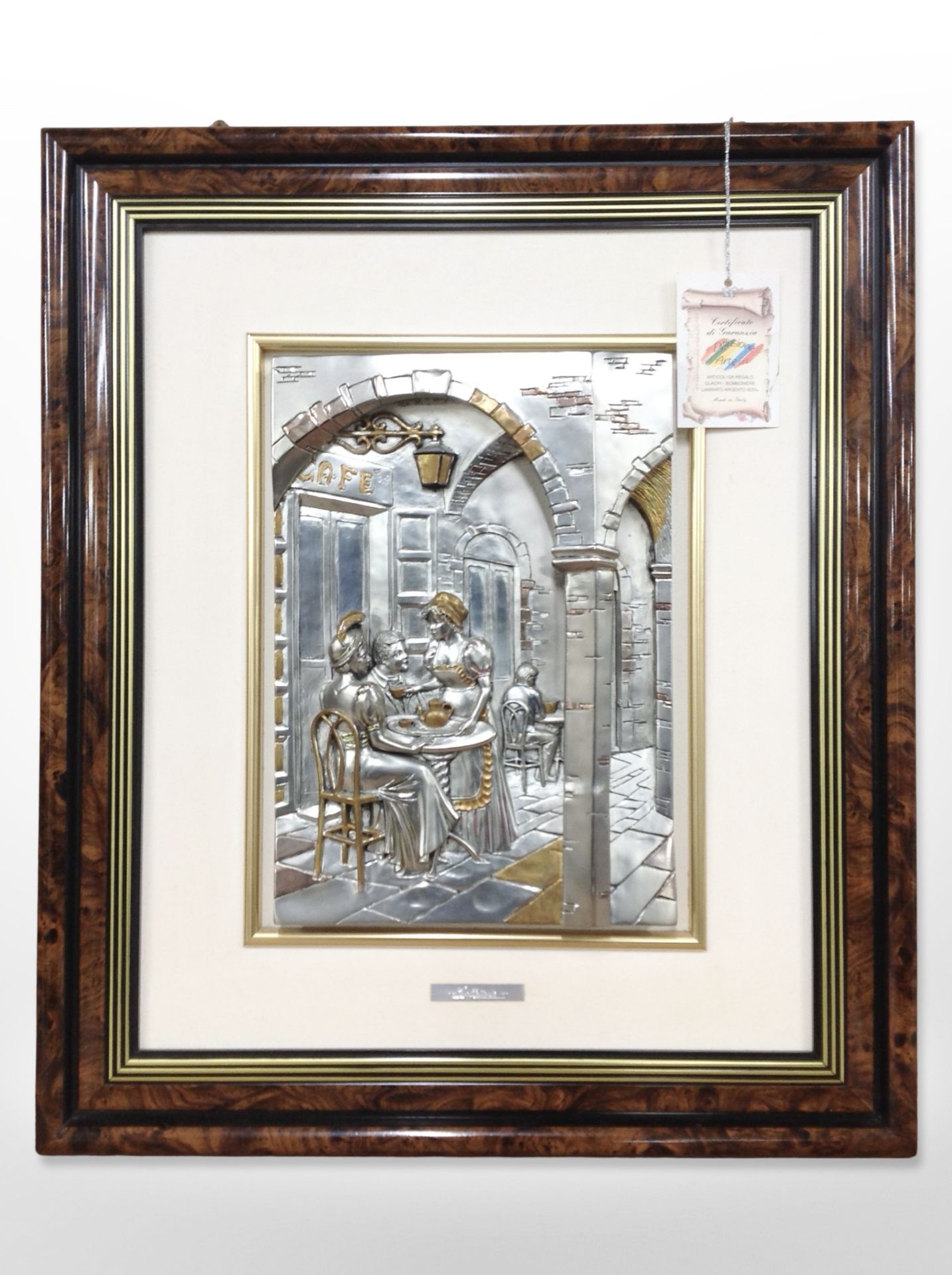 An Italian embossed silver relief picture depicting figures in a café between stone pillars,