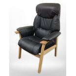 A contemporary Scandinavian oak-framed black leather armchair.