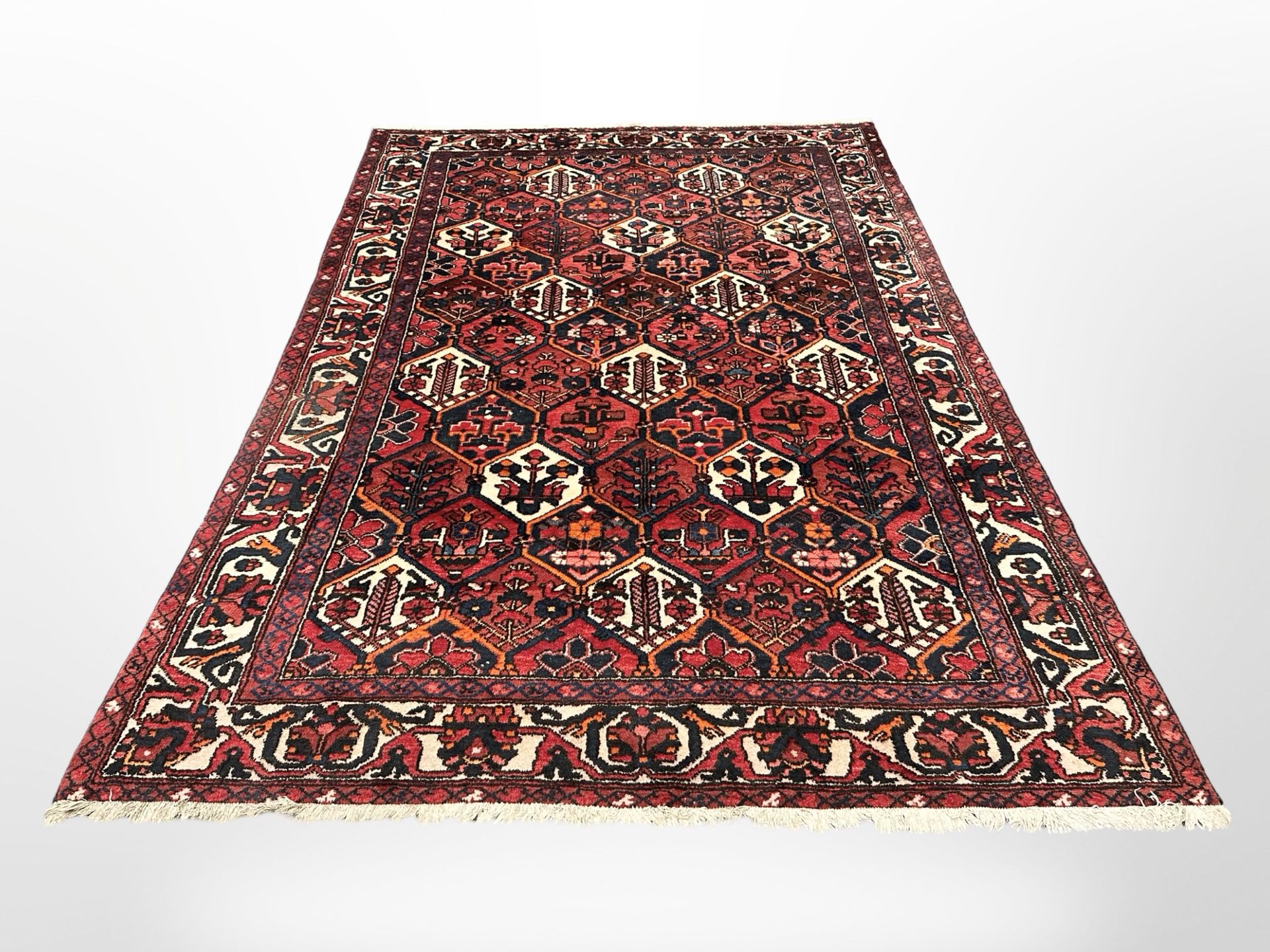 A Bakhtiari carpet, West Iran, the central madder and ivory lattice field of stylised flowers,