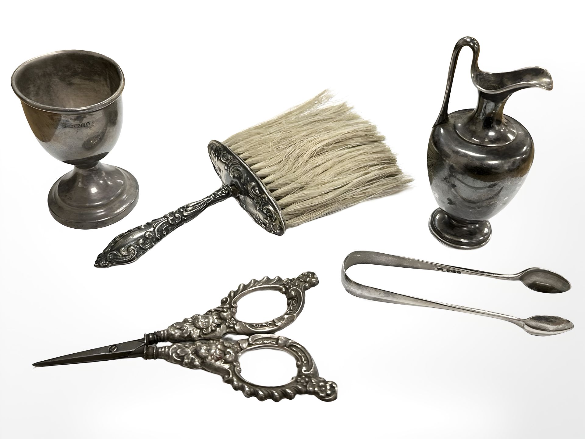 A silver egg cup, small jug, pair of sugar nips, silver-mounted brush and similar scissors.