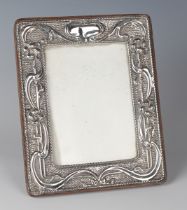 An Edwardian silver mounted rectangular photograph frame, embossed with flowers and scrolling