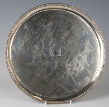 A George III silver circular card salver, the centre crest engraved within a beaded rim, raised on