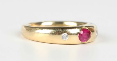 An 18ct gold, ruby and diamond ring, mounted with the oval cut ruby between two gypsy set circular