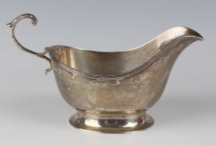 A George V silver sauceboat with reeded rim and flying scroll handle, on an oval foot, Sheffield