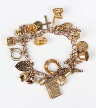 A gold curblink charm bracelet on a 9ct gold heart shaped padlock clasp, fitted with twenty-two