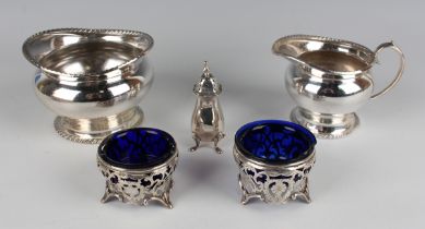 A pair of Edwardian silver circular salts with engraved and pierced scroll decoration, on scroll